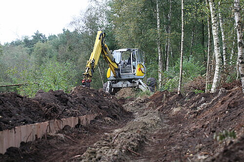 Einbau einer Spundwand und Lehmschürze mit Schreitbagger